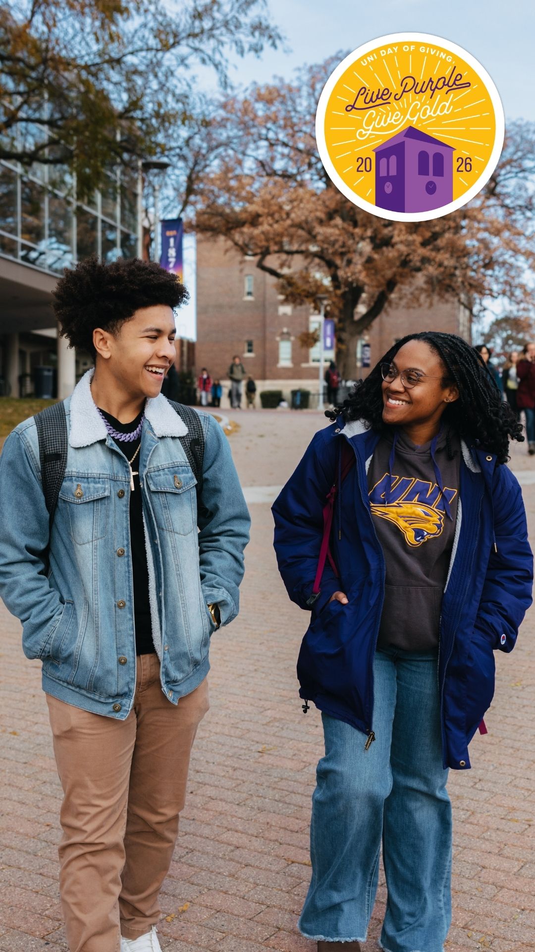 Two students walking on campus with the Live Purple Give Gold logo in the top right corner.