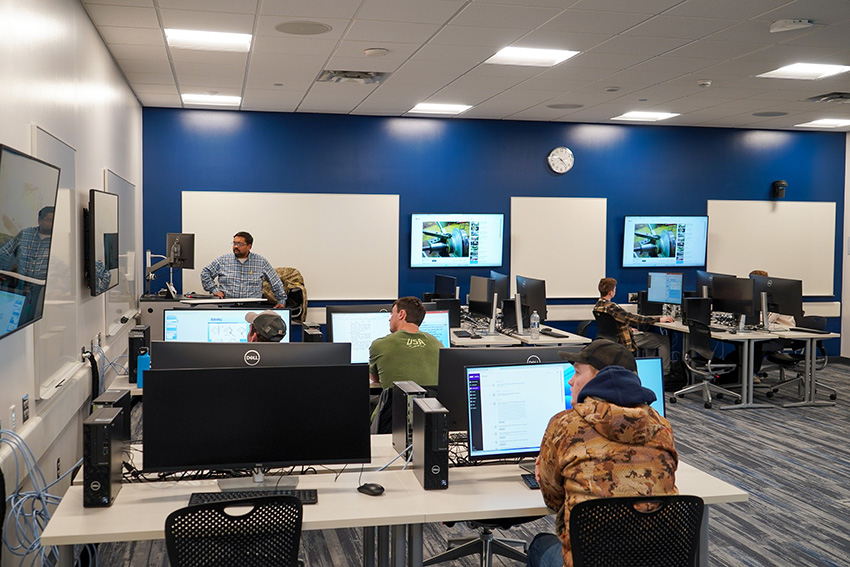 UNI professor teaching a classroom of students working on computers